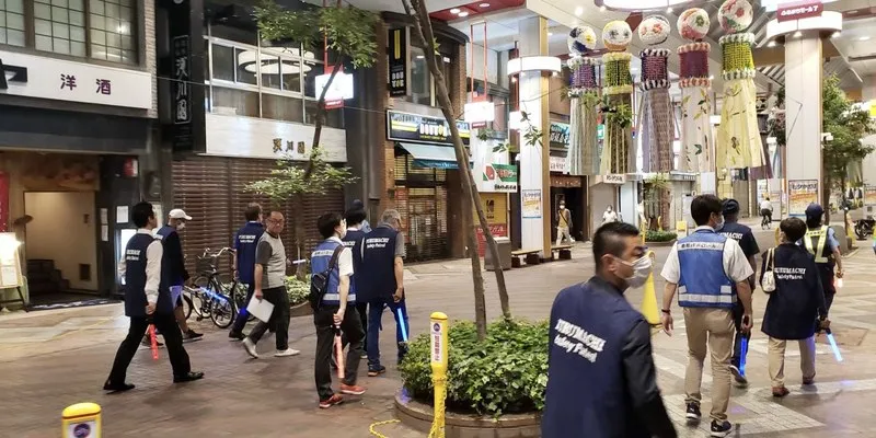 ライトを持って古町の商店街を歩く参加者。七夕の飾りが下がっている