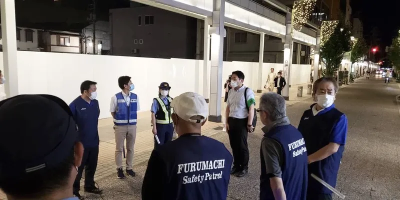 警察官とともに古町の通りを確認する参加者。古町安全パトロールのベストを着ている